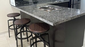 A modern kitchen with a central island, bar stools, a built-in oven, and a refrigerator. - Ocean view 1 block from the malecon beach (Mazatlan)