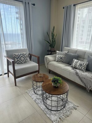 Ein Wohnzimmer mit Sofa, Sessel, Couchtisch und einer Topfpflanze.
