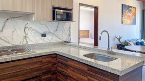 A modern kitchen with a marble backsplash, wooden cabinets, a built-in microwave, and a sink. - Charming Apartment w/ Pool 3 Blocks to Beach (Mazatlan)