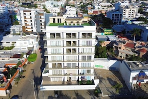 A multi-story hotel with balconies, a rooftop terrace, and a green lawn. - Beautiful apartment steps from the beach (Mazatlan)