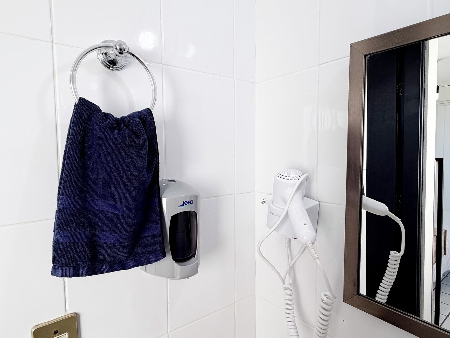 Un baño con toallero, secador de pelo y espejo.