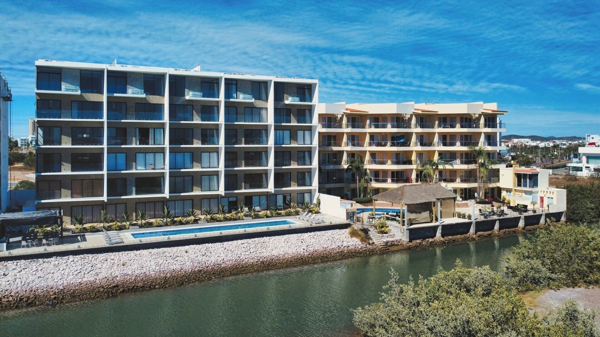 A multi-story hotel with balconies, a swimming pool, and a river view.