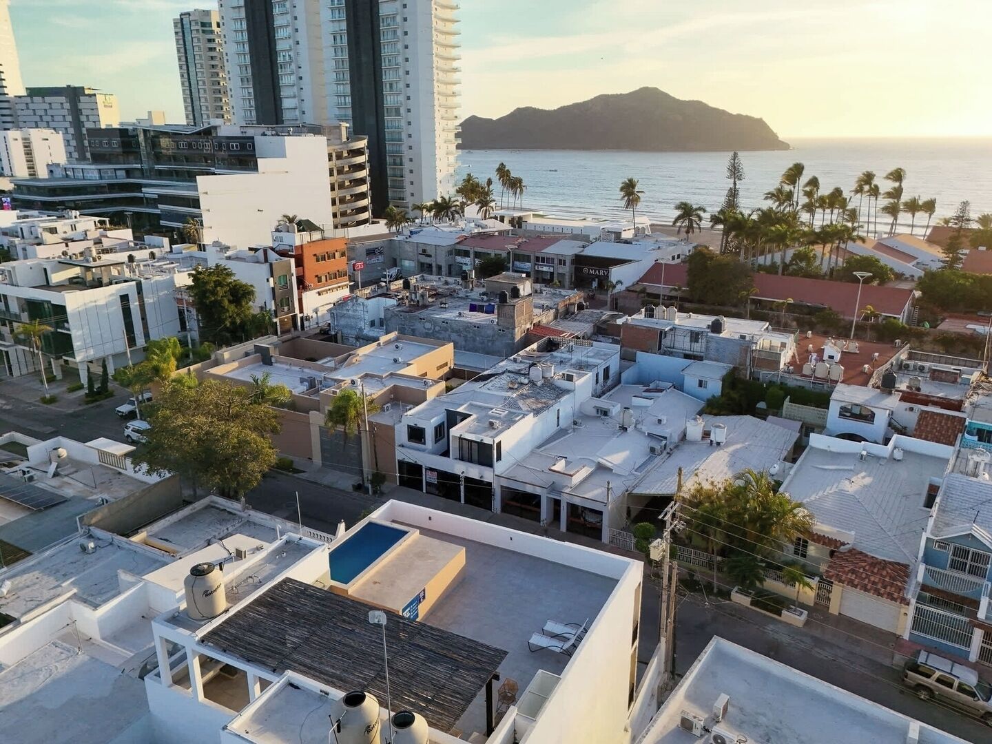 An urban area with buildings, a beach, and a mountain in the background.
