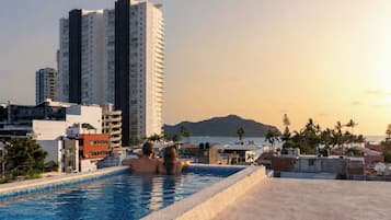 Una piscina en la azotea con vistas a un paisaje urbano y una montaña en la lejanía.