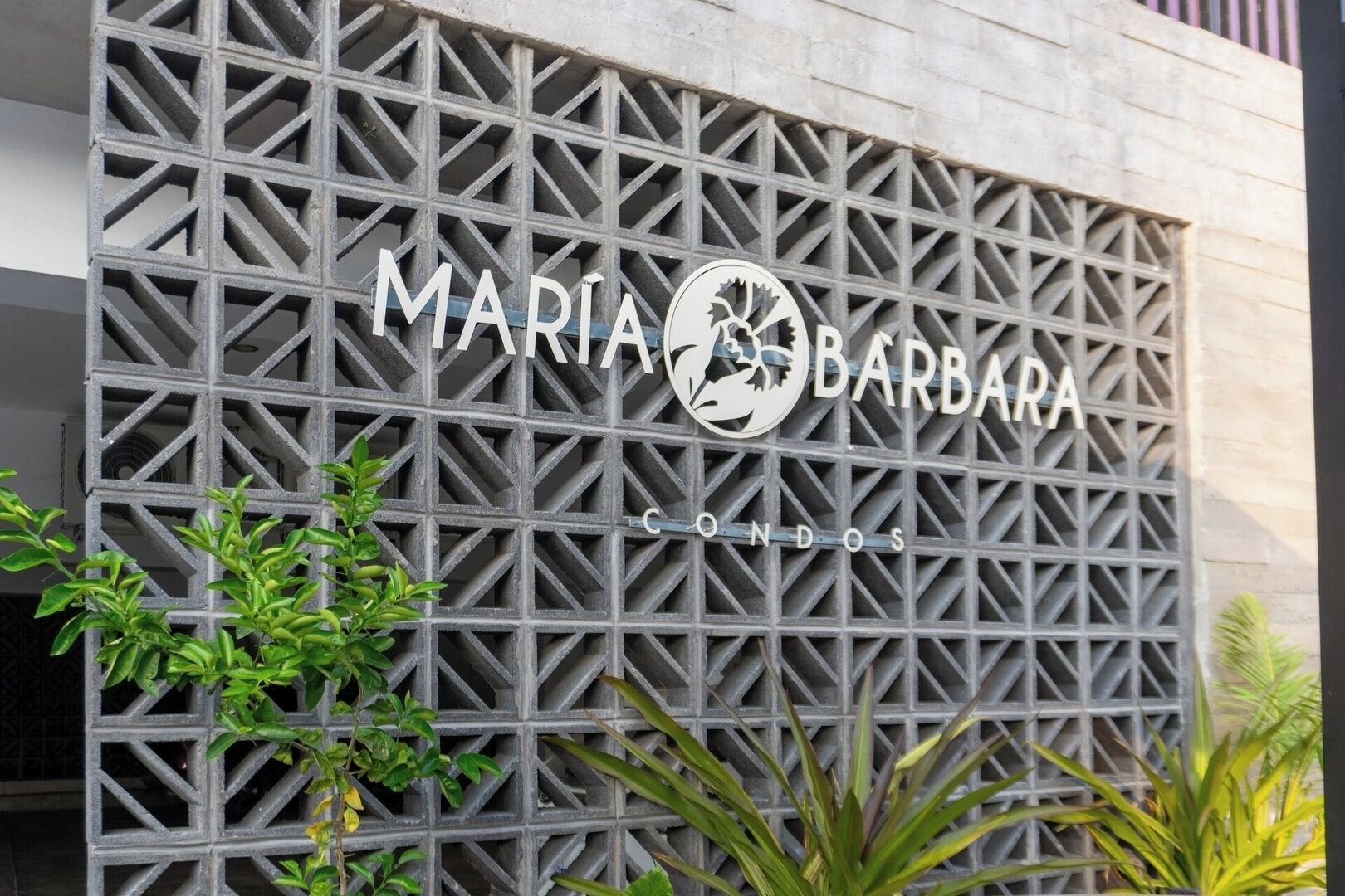 Une façade d’immeuble ornée d’un motif géométrique en métal et sur laquelle figure en grand le nom « MARIA BARBARA CONDOS ».