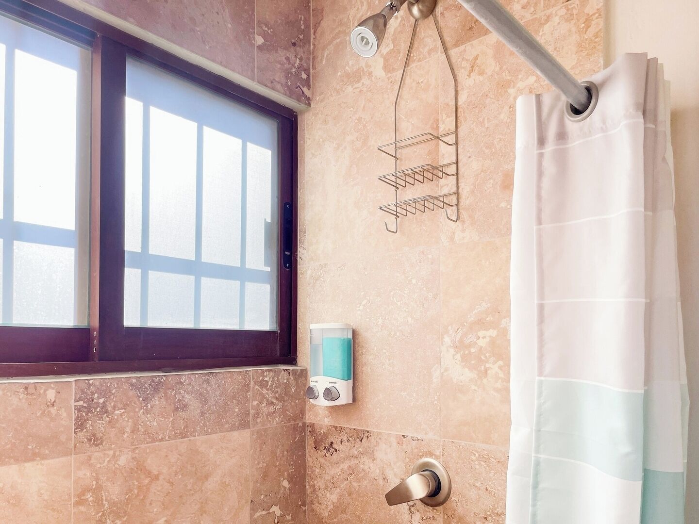 Une salle de bain avec une fenêtre, un rideau de douche, un porte-serviettes et un distributeur de savon.