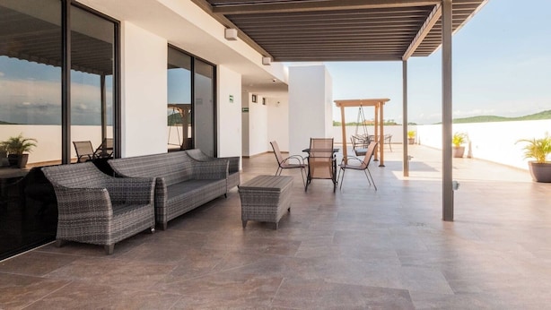A covered outdoor seating area with a sofa, chairs, and a table, overlooking a body of water. - Family-Friendly Apartment near Mazatlan Beach (Mazatlan)