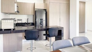 A modern kitchen with a built-in refrigerator, a toaster, and a bar area with two chairs. - Family-Friendly Apartment near Mazatlan Beach (Mazatlan)