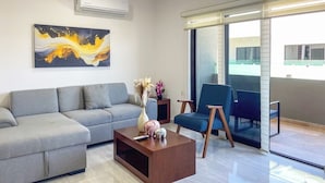 A modern living room with a grey sofa, a wooden coffee table, and a blue armchair. - Family-Friendly Apartment near Mazatlan Beach (Mazatlan)