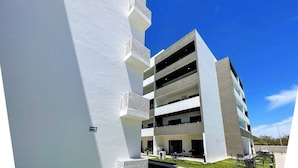 A modern building with multiple floors, outdoor seating, and a clear sky. - Family-Friendly Apartment near Mazatlan Beach (Mazatlan)