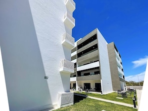A modern building with multiple floors, outdoor seating, and a clear sky. - Family-Friendly Apartment near Mazatlan Beach (Mazatlan)
