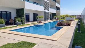 A modern building with a swimming pool, outdoor seating, and greenery. - Family-Friendly Apartment near Mazatlan Beach (Mazatlan)