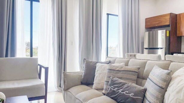 A modern living room with a sofa, a chair, and a dining table. - Beautiful apartment 3 blocks from the beach (Mazatlan)