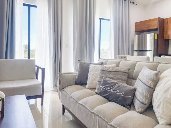 A modern living room with a sofa, a chair, and a dining table. - Beautiful apartment 3 blocks from the beach (Mazatlan)