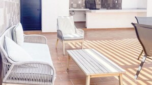 A modern living area with a sofa, a chair, a small table, and a reception desk. - Beautiful apartment 3 blocks from the beach (Mazatlan)
