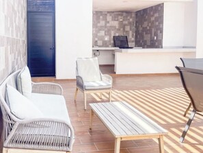 A modern living area with a sofa, a chair, a small table, and a reception desk. - Beautiful apartment 3 blocks from the beach (Mazatlan)