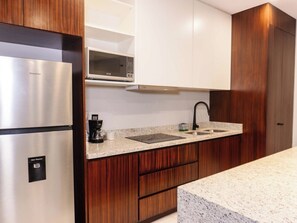 Eine moderne Küche mit einem Edelstahl-Kühlschrank, einer Mikrowelle, einer Spüle mit schwarzem Wasserhahn und Holzschränken.