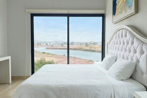 Ein Schlafzimmer mit großem Fenster, einem Bett und einem Bild an der Wand.
