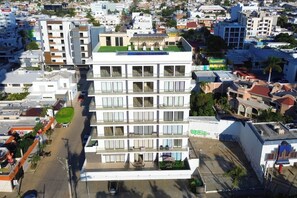 Ein mehrstöckiges Hotel mit Balkonen, einer Dachterrasse und einer grünen Rasenfläche.