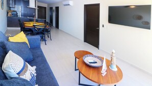 Ett modernt vardagsrum med en soffa, ett soffbord och en matplats med stolar och ett bord.