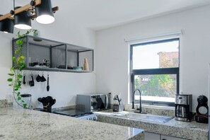 Una cucina moderna con piani in granito, forno integrato, macchina del caffè e una finestra con vista.