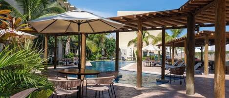 Un espace piscine équipé de chaises longues, de parasols et d’une table de billard.