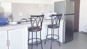 A kitchen with two bar stools, a refrigerator, a microwave, and a stove. - Roma Suite A Malecon de Mazatlán (Mazatlán)