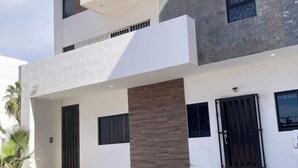 A multi-story building with a modern architectural design, featuring a flat roof, large windows, and a prominent entrance with a dark door. - Roma Suite A Malecon de Mazatlán (Mazatlán)