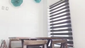 A dining area with a table and chairs, a window with horizontal blinds, and two wall-mounted decorative items. - Roma Suite A Malecon de Mazatlán (Mazatlán)