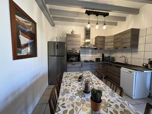 Uma cozinha moderna com mesa de jantar, cadeiras, geladeira, forno, micro-ondas e lava-louças.