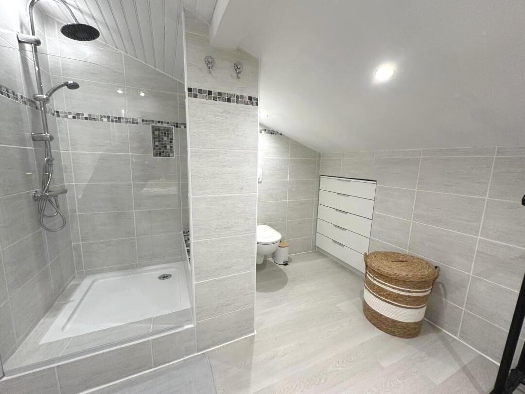 A modern bathroom with a glass-enclosed shower, a toilet, and a storage cabinet.