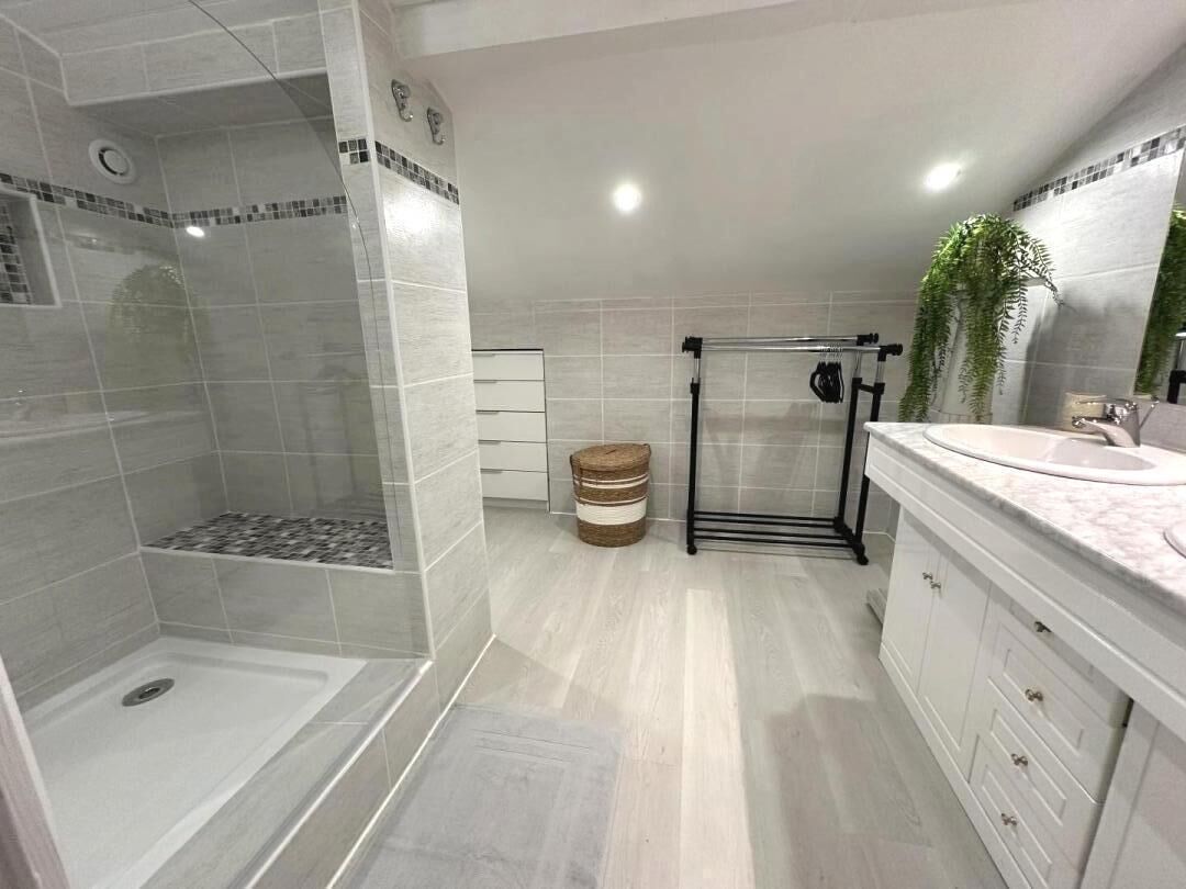 Ein modernes Badezimmer mit Dusche, Waschtisch und Spiegel.