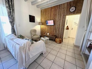 Uma sala de estar com sofá, poltrona, televisão e uma parede de destaque em madeira.