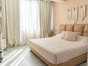 Ein Hotelzimmer mit einem großen Bett, einem Kopfteil, einem Nachttisch und einer Wanddekoration aus Makramee.