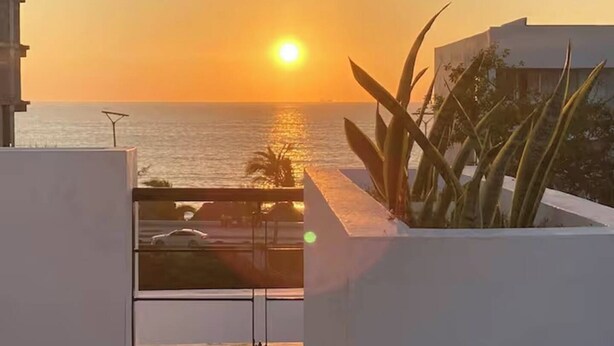 Een balkon met uitzicht op de oceaan bij zonsondergang.