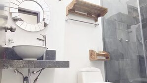 Een moderne badkamer met een ronde spiegel, een wastafel, een toilet en een douchecabine.