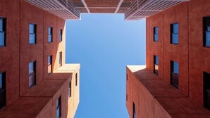 Ein modernes Gebäude mit einer symmetrischen Fassade, zahlreichen Fenstern und wolkenlosem Himmel.