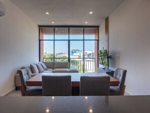 Ein moderner Konferenzraum mit langem Tisch und Stühlen, großen Fenstern mit Stadtblick und deckenintegraler Beleuchtung.