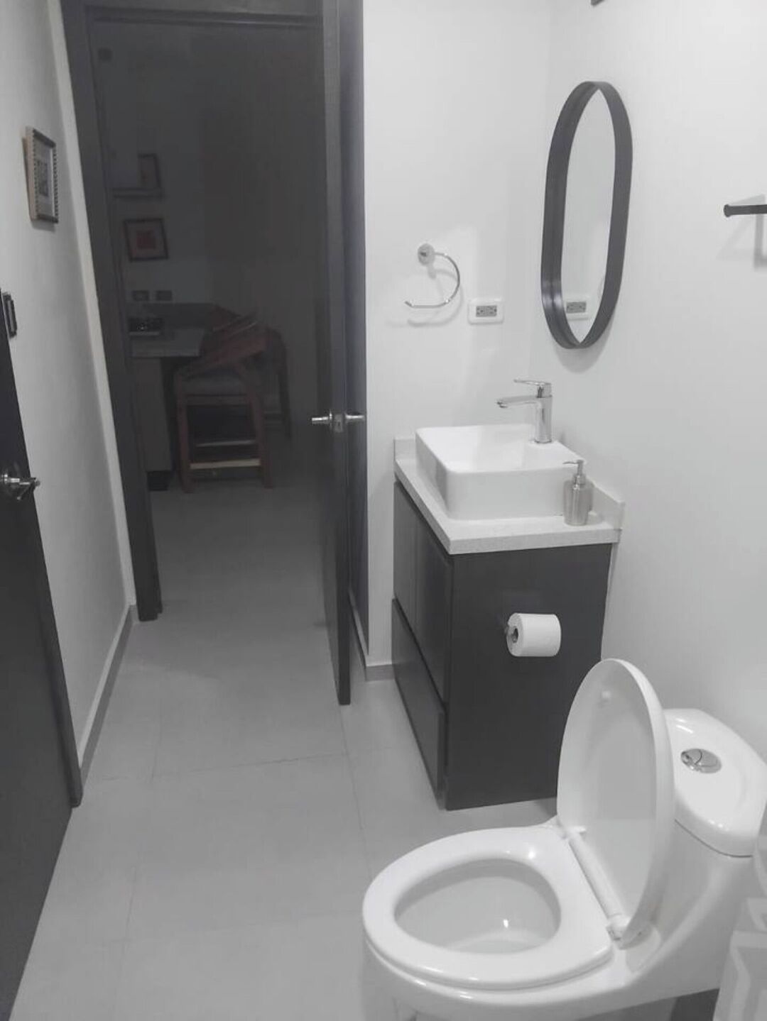 A bathroom with a toilet, sink, and mirror.