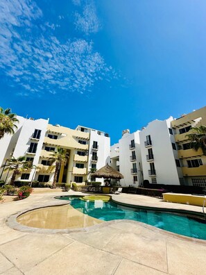 Ein Resort mit Pool, Palmen und mehrstöckigen Gebäuden.