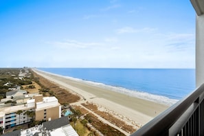 Eine Küstenansicht mit Strand, Ozean und Gebäuden im Hintergrund.