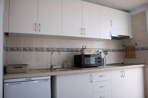 A kitchen with white cabinets, a microwave, a sink, and a dish rack. - Front line beach penthouse with large terrace facing the sea! (Puerto de la Cruz)