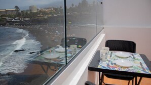 A balcony with a table set for two, overlooking a beach with people and umbrellas. - Front line beach penthouse with large terrace facing the sea! (Puerto de la Cruz)