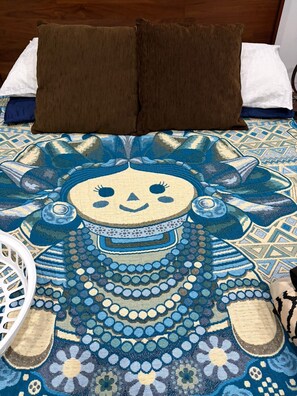 A bed with a patterned bedspread, two brown pillows, and a white chair. - RIAD LA FIBULA DE NORA (Fes)