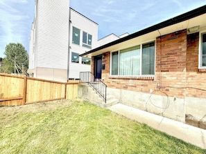 A residential building with a brick facade, a wooden fence, and a grassy yard. - Modern 2BR Retreat near Light Rail, Seward Park 52 (Seattle)