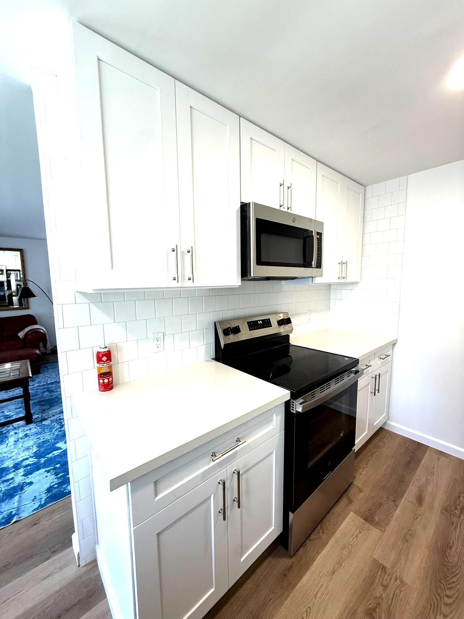 A kitchen with white cabinets, a black stove, and a microwave.