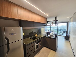 Cozinha moderna com forno embutido, geladeira e uma grande janela com vista para a cidade.