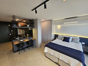 Une chambre d’hôtel moderne équipée d’un lit, d’un bureau et d’une kitchenette.