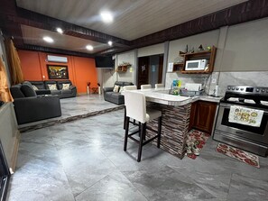 A modern kitchen with a central island, built-in microwave, and stainless steel appliances. - Casa Del Sol: Privacy, comfort and unforgettable moments. (Provincia de Guanacaste)