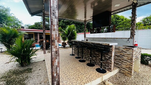Un espace bar extérieur agrémenté d’une colonne en pierre, d’une piscine et d’un coin salon abrité.